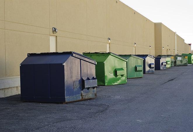 a construction worker unloading debris into a blue dumpster in Mattapan MA